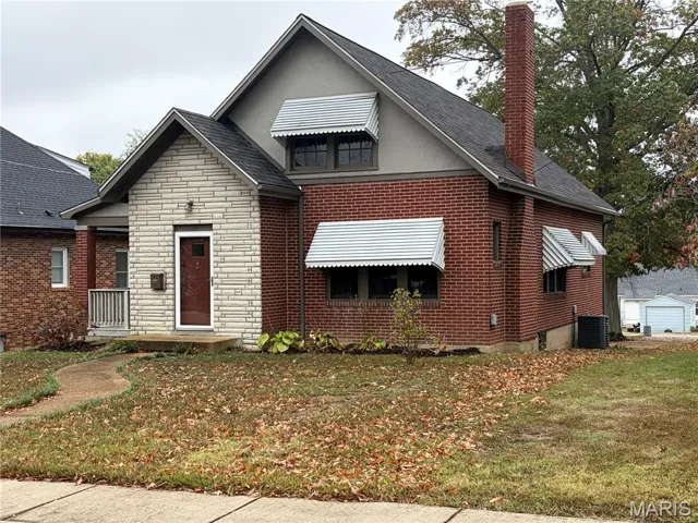 View of front of home with a chimney, a front lawn, stone siding, crawl space, and brick siding