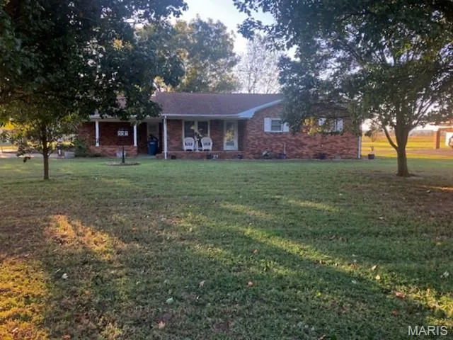 Ranch-style house featuring a front yard, covered porch, and brick siding