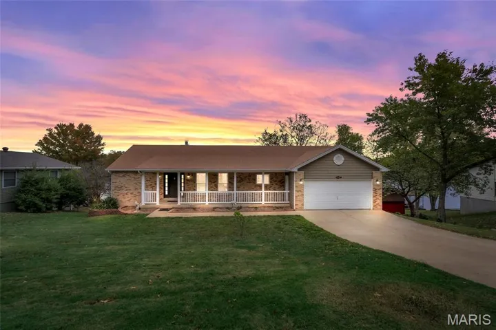 Ranch-style home featuring a porch, driveway, brick siding, a lawn, and a garage