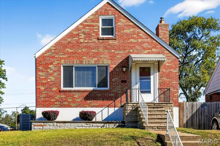 View of front of property featuring a chimney and brick siding