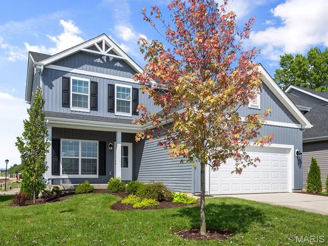 View of front of property with a front lawn, a porch, driveway, and board and batten siding