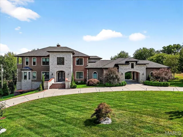 French country inspired facade featuring a front lawn, a chimney, and stone siding