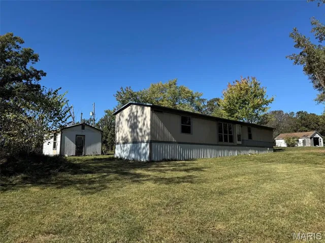 View of home's exterior with a yard and an outdoor structure