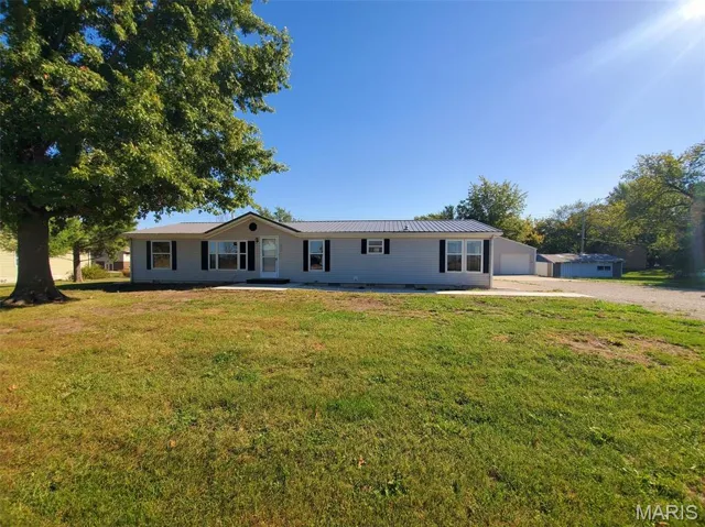 Ranch-style home with a metal roof, a front yard, a garage, and a standing seam roof