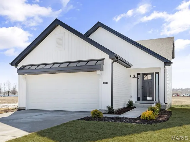 View of front of property featuring concrete driveway, a garage, a standing seam roof, a metal roof, and a front yard