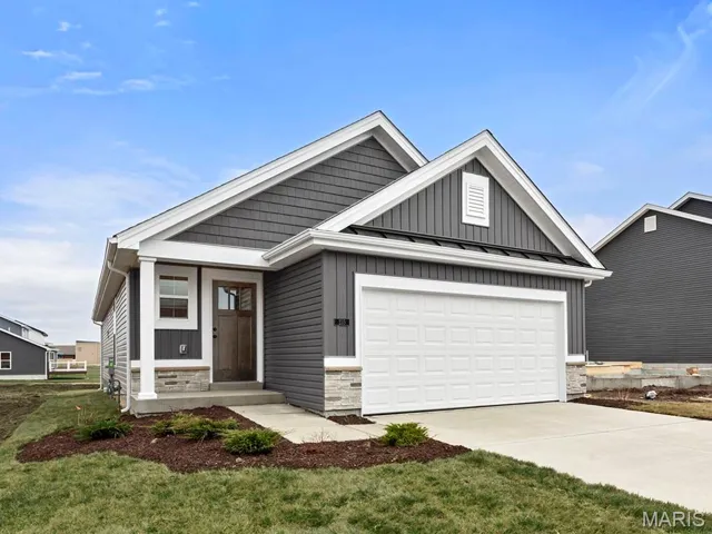 View of front of property with stone siding, concrete driveway, a metal roof, a standing seam roof, and board and batten siding