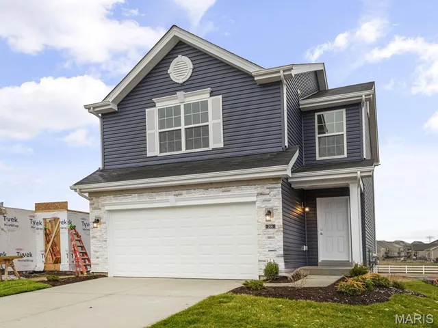 View of front facade featuring stone siding, a garage, and concrete driveway