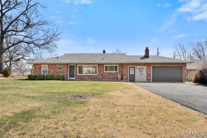 Ranch-style home with driveway, a front lawn, an attached garage, and brick siding