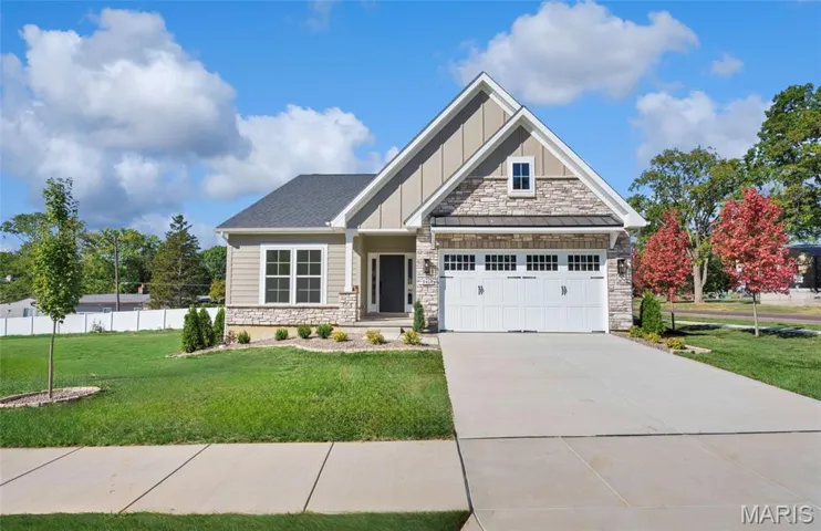 Craftsman-style house with stone siding, board and batten siding, driveway, and an attached garage