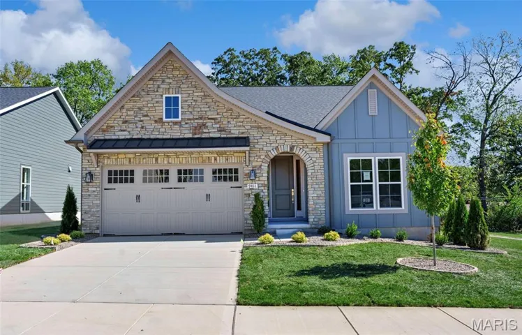 View of front of property featuring board and batten siding, stone siding, a front yard, and driveway