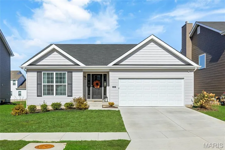 View of front of home with a front yard, concrete driveway, and a garage