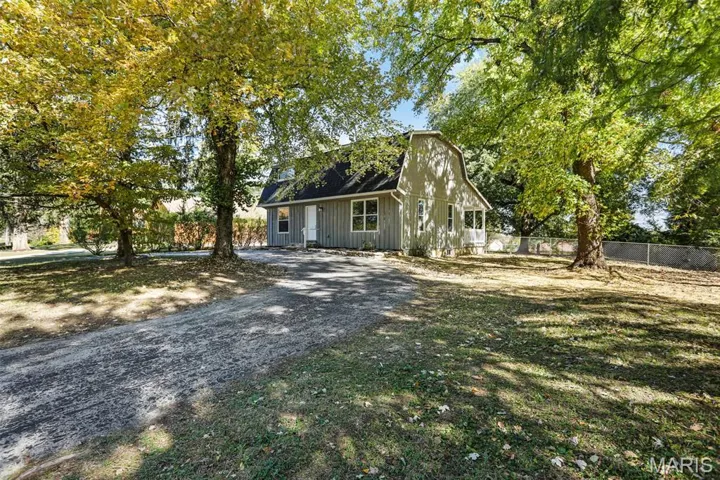 View of front of property featuring a gambrel roof, driveway, and a shingled roof