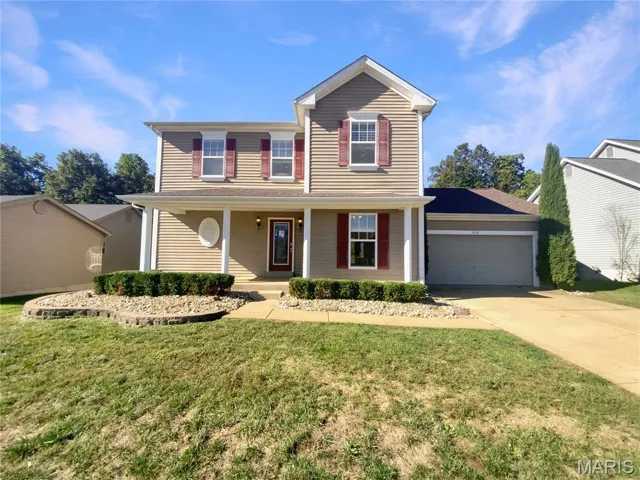 Traditional-style home with a porch, concrete driveway, a front yard, and a garage