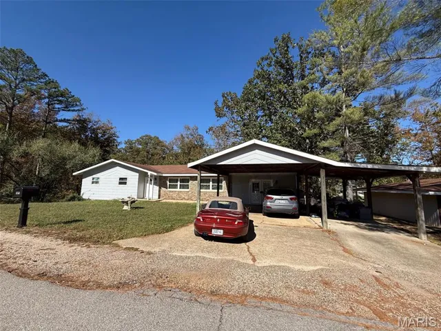 Single story home featuring a front yard, driveway, and an attached carport