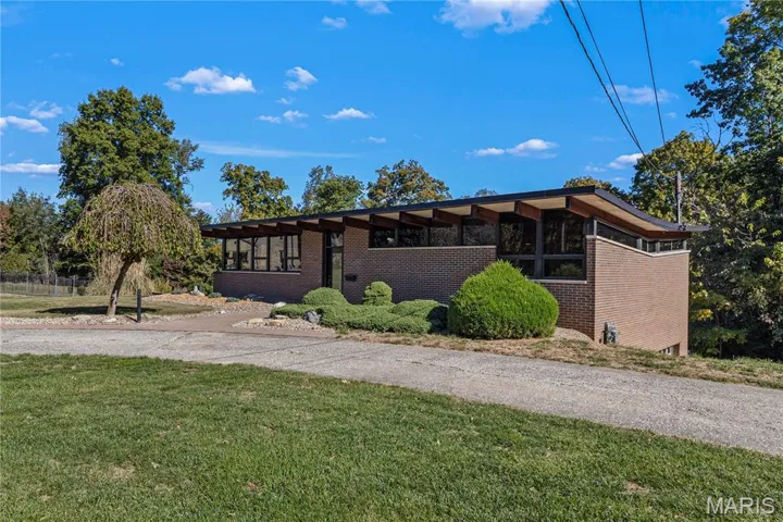 Mid-century inspired home with brick siding and a front lawn