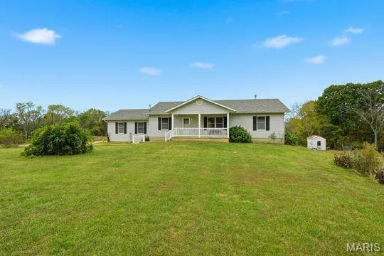 View of front facade featuring covered porch and a front lawn