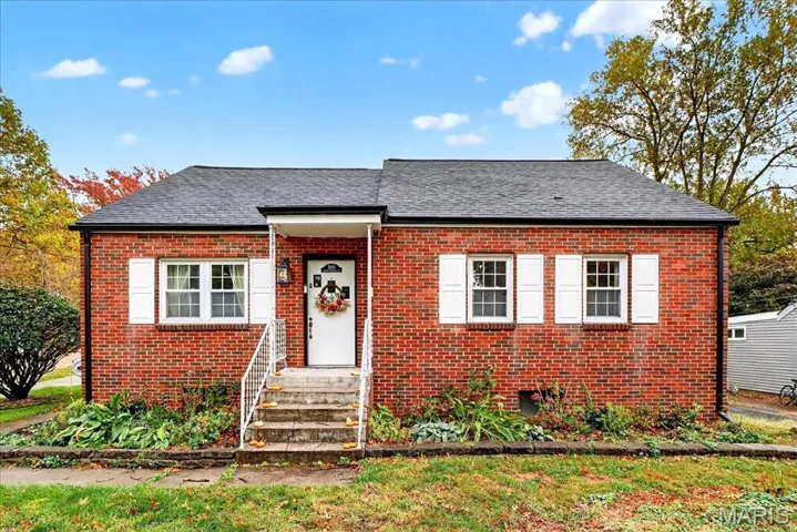 View of front facade with brick siding and a shingled roof