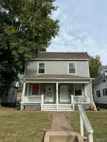 View of front of house featuring covered porch, a front lawn, and roof with shingles