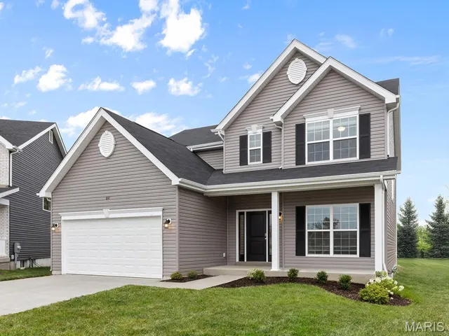 Traditional-style home with covered porch, a front yard, driveway, and a garage