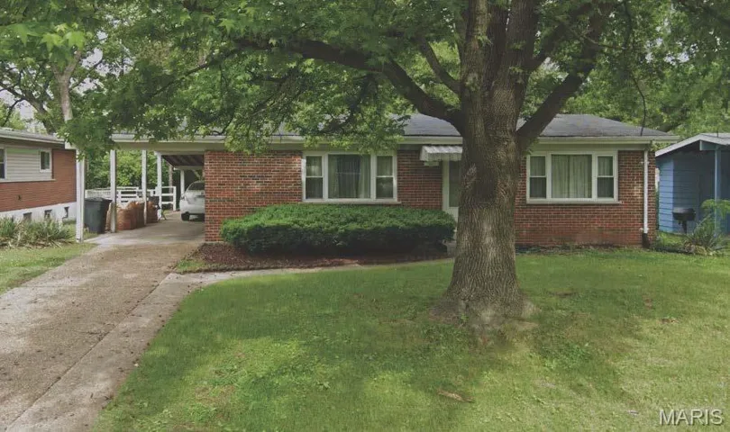 View of front facade with driveway, a front yard, and brick siding