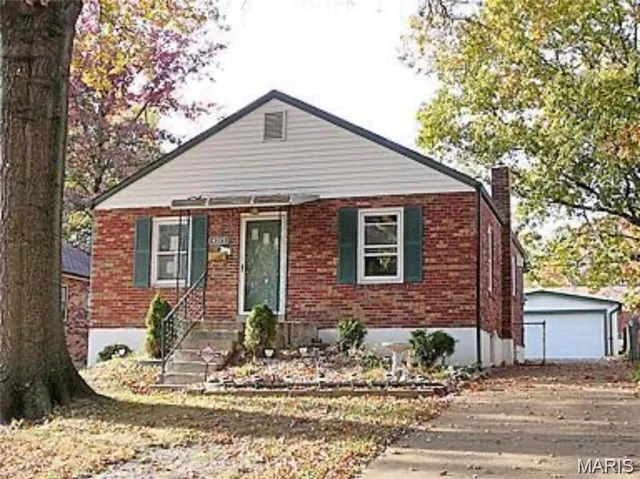 Bungalow-style house featuring an outdoor structure, brick siding, a chimney, and a detached garage