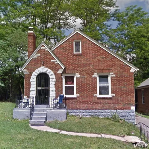 View of front of property with brick siding, a chimney, and a front yard