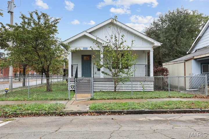 View of front of property with a gate, a fenced front yard, and a porch