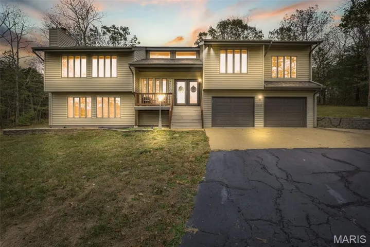 View of front of house with driveway, a front lawn, a garage, and a chimney