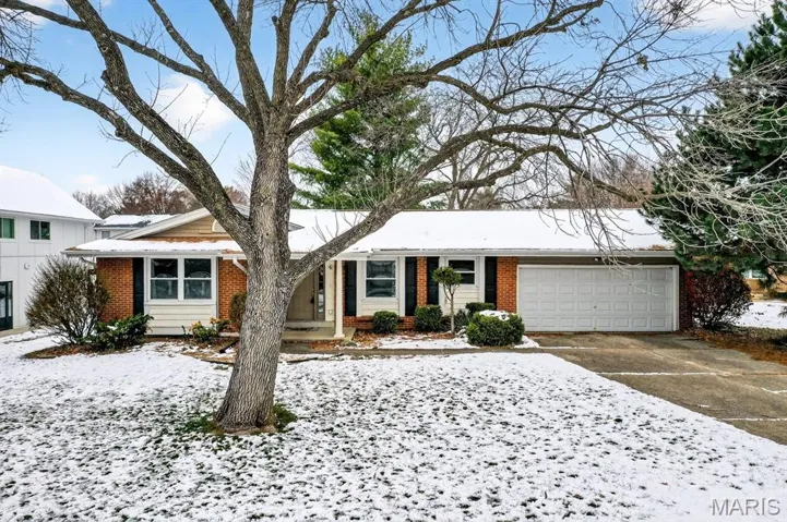 Single story home featuring brick siding, concrete driveway, covered porch, and an attached garage