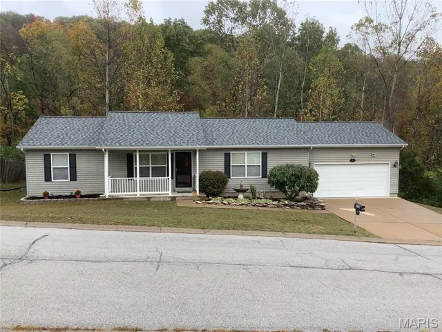 Ranch-style house with covered porch, a shingled roof, driveway, and a garage