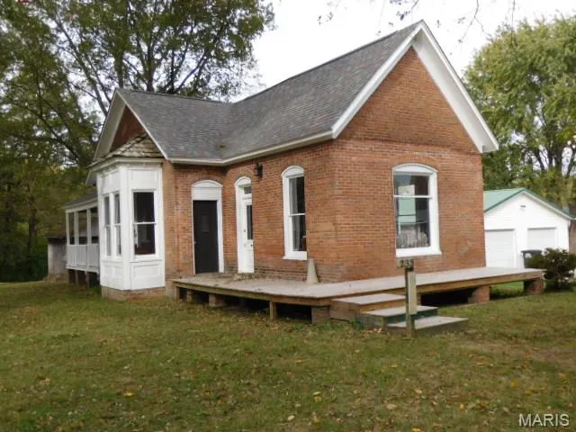 View of front of house with a front yard, a deck, a garage, and brick siding