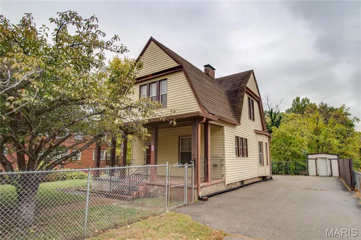 View of front of house with a gambrel roof, a chimney, a shingled roof, an outbuilding, and covered porch