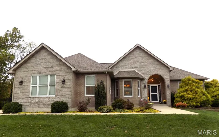 View of front of house with a front yard, stone siding, a shingled roof, and brick siding