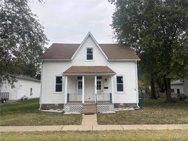 View of front of home with a front yard, covered porch, roof with shingles, and crawl space