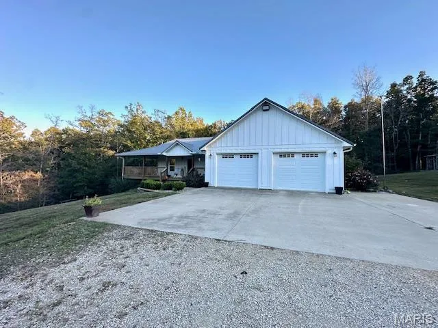 Single story home featuring driveway, a garage, a front yard, and board and batten siding