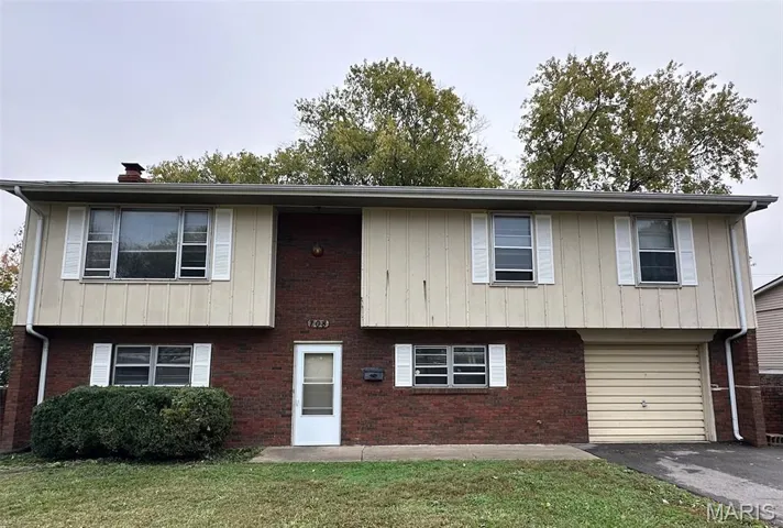 View of front facade featuring brick siding, a front yard, a chimney, a garage, and asphalt driveway