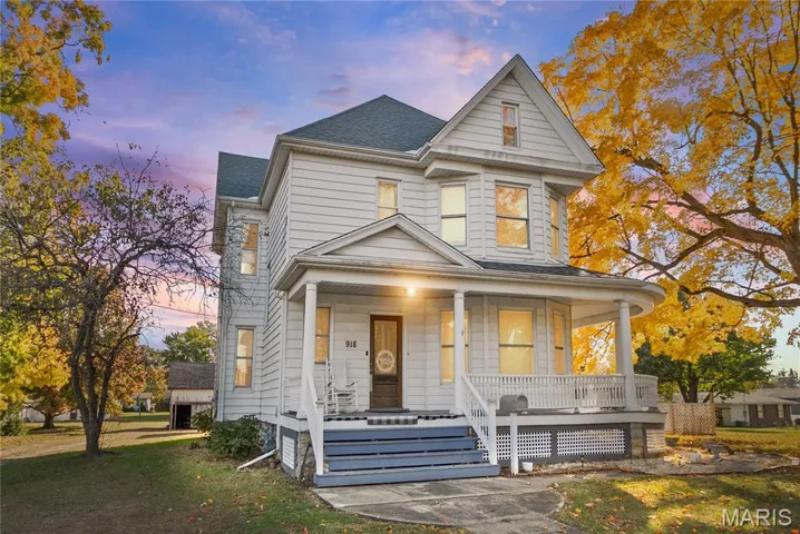 View of front facade with a porch, a shingled roof, and a front lawn