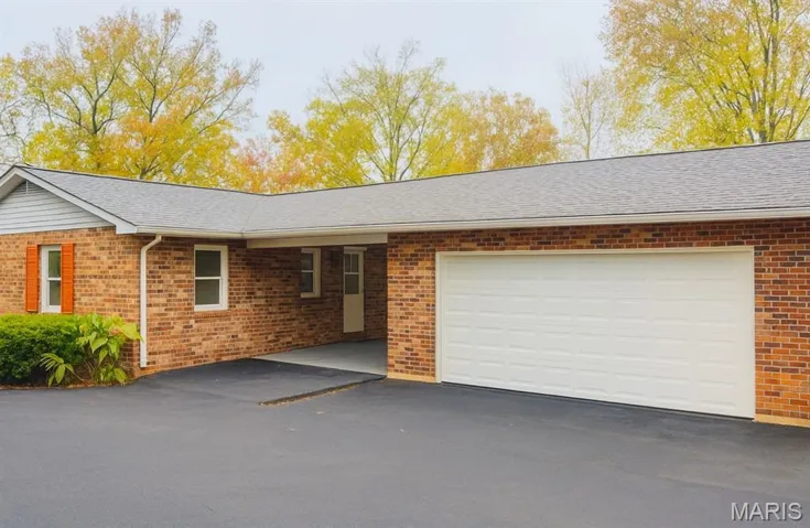 Single story home with driveway, brick siding, and a shingled roof