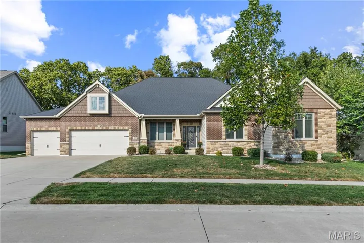 Craftsman-style home with stone siding, a porch, a front yard, driveway, and a garage