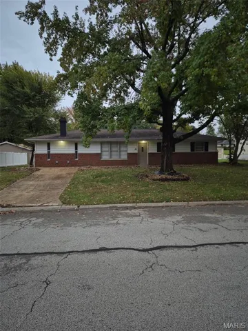 Ranch-style house with a front lawn, a chimney, brick siding, and driveway