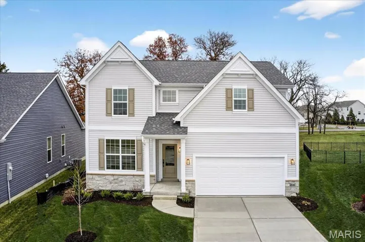 Traditional-style house with stone siding, a shingled roof, concrete driveway, and an attached garage