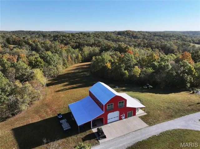 Aerial view of property and surrounding area featuring a heavily wooded area
