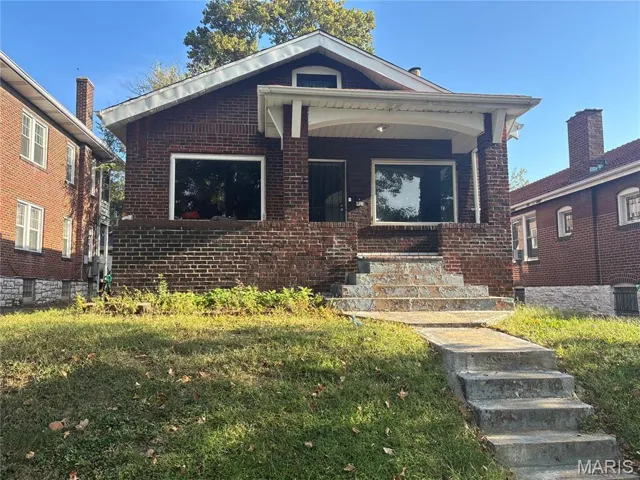 Bungalow-style house with a front yard, covered porch, and brick siding