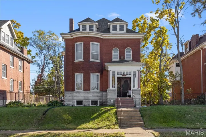View of front of property featuring brick siding and a chimney