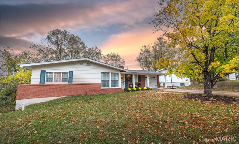 Ranch-style house featuring a lawn, a garage, brick siding, and driveway