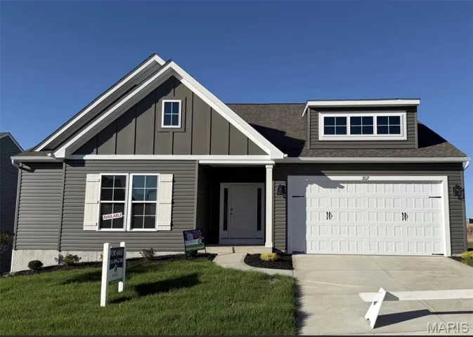 View of front of house featuring board and batten siding, a front yard, driveway, a garage, and roof with shingles
