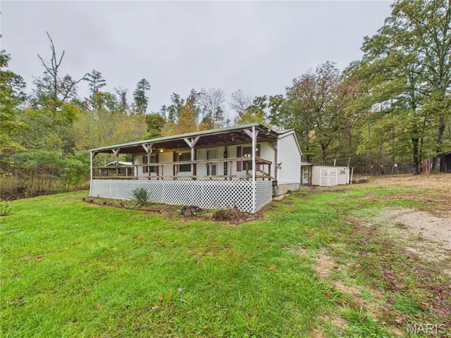 View of front of property with a front yard, a deck, and a storage unit