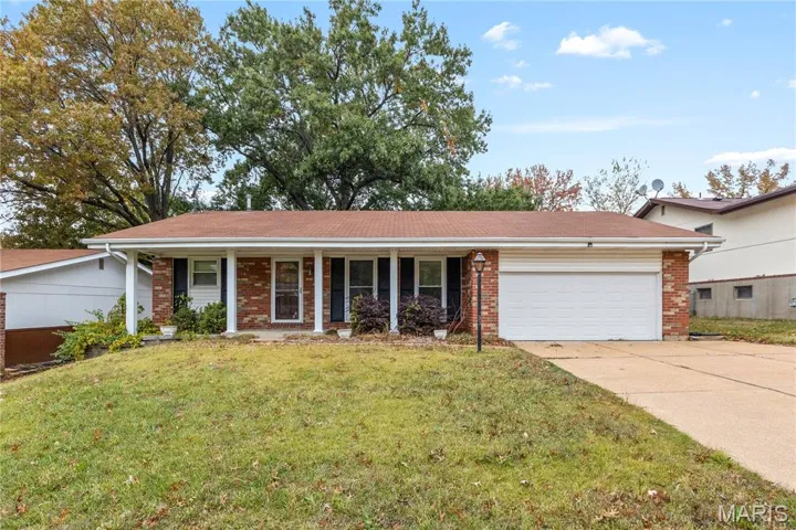 Ranch-style house with brick siding, a porch, a garage, and a front yard