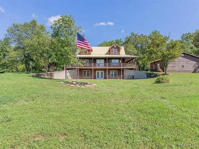 Back of property with a lawn, a porch, a metal roof, and french doors