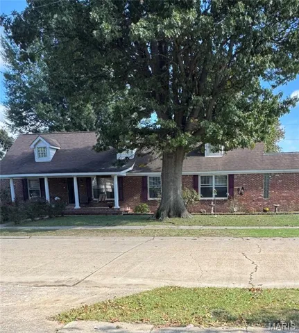 View of front facade featuring a porch, brick siding, and a shingled roof